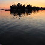 Sonnenuntergangsfarben auf dem Wasser mit einer Insel im Hintergrund
